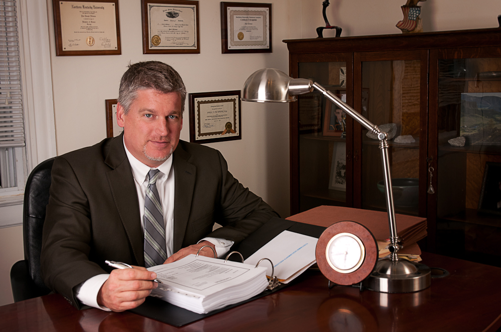 Attorney Paul J. Dickman standing at his desk at the Dickman Law Office